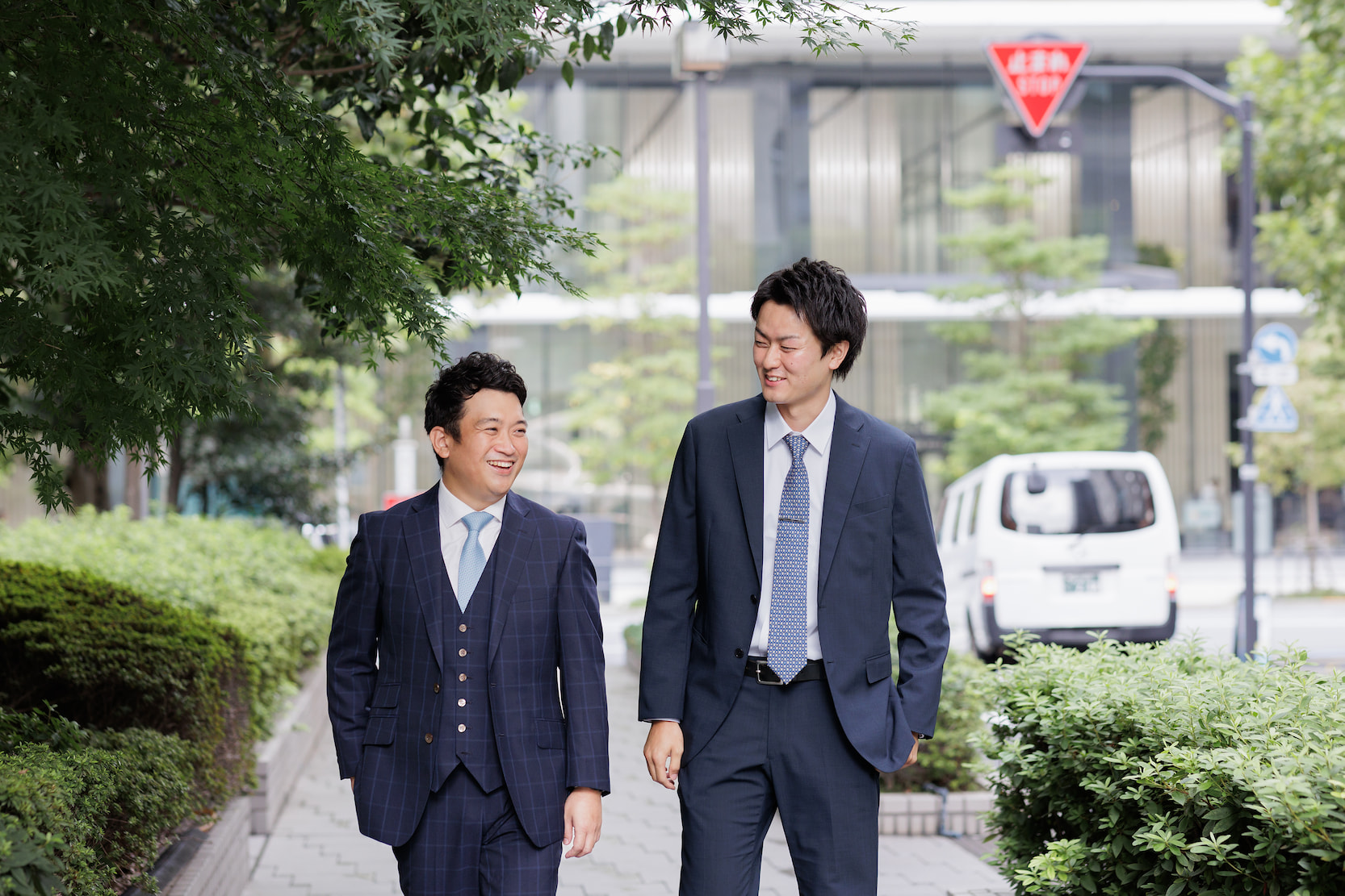 社員2名が会社の表通りを話しながら歩いている様子